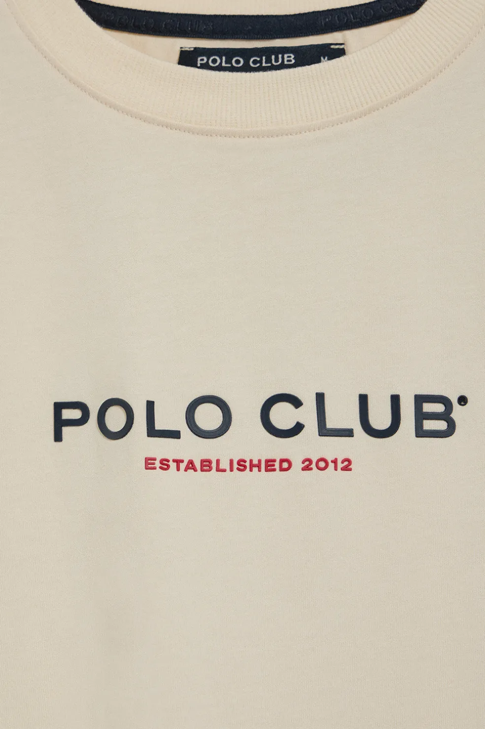 Camiseta color crudo de cuello redondo y logo engomado