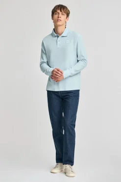 Polo azul claro de manga larga y dos botones con parche logotipado