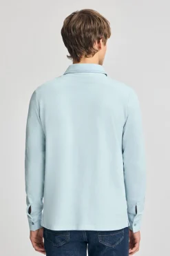Polo azul claro de manga larga y dos botones con parche logotipado