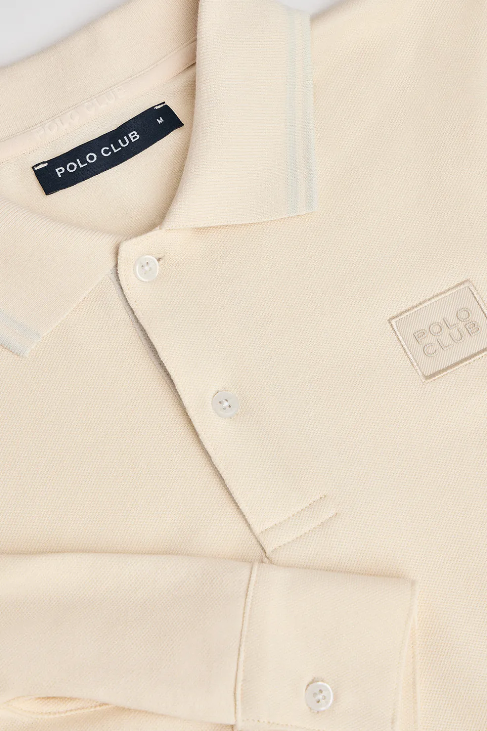 Polo color crudo de manga larga y dos botones con parche logotipado